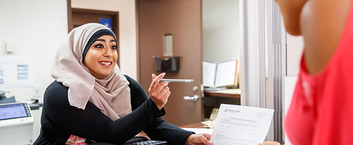 Student receiving a document from staff member